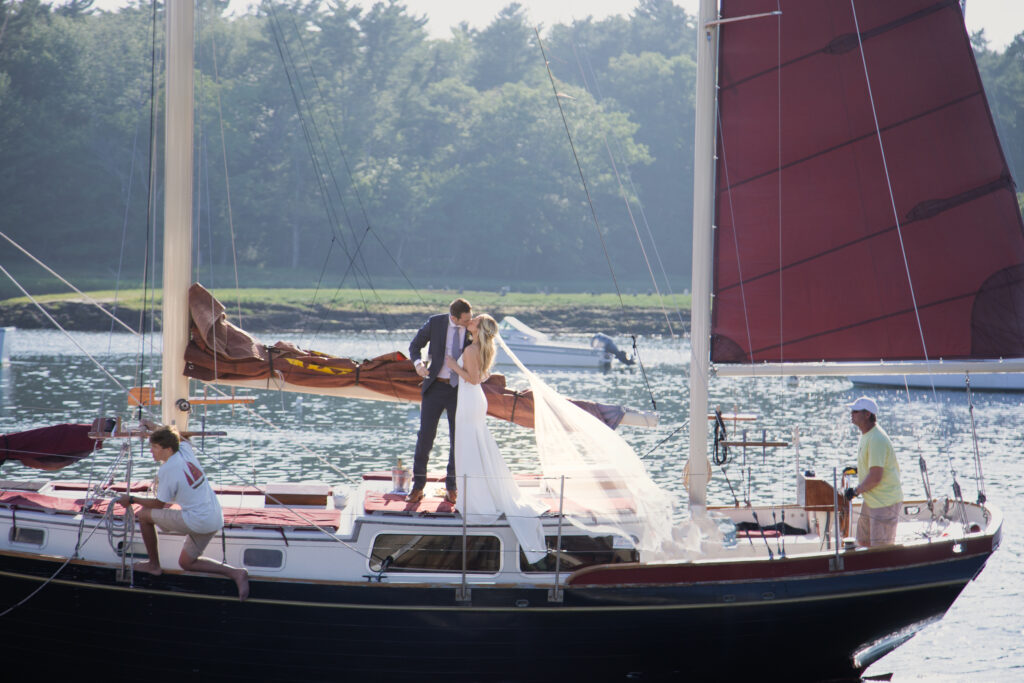 bride and groom kissing while arriving at ceremony on sailboat 