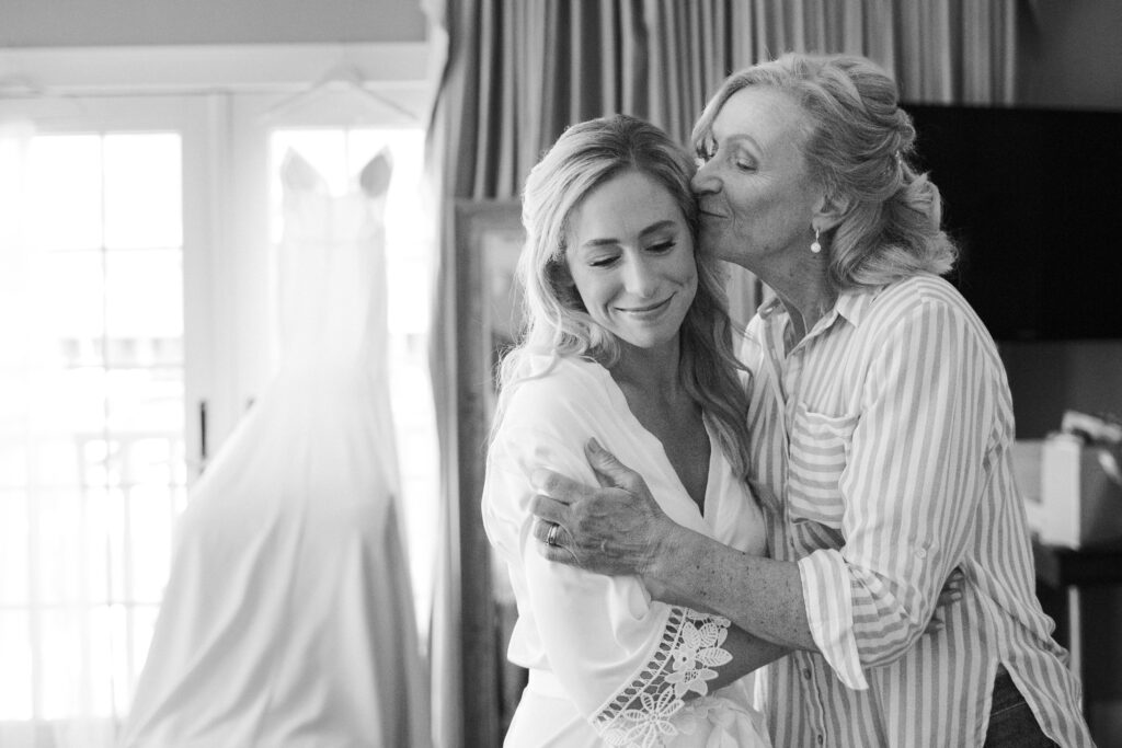 black and white of brides mom kissing her on the cheek 