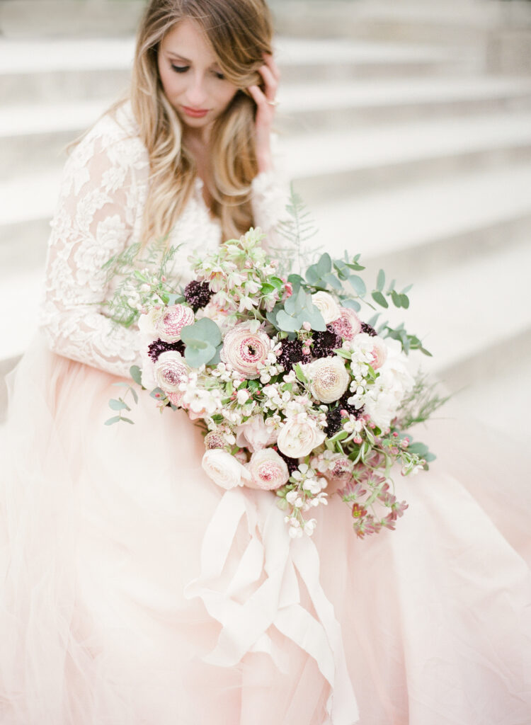 bride sitting on steps in jardin de luxembourg with romantic bouquet 