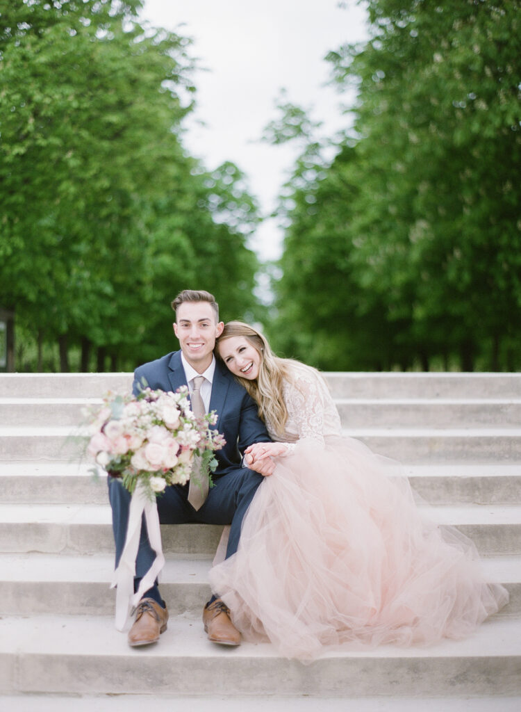 bride leaning on grooms shoulder sitting next to each other on the steps at jardin de luxembourg 