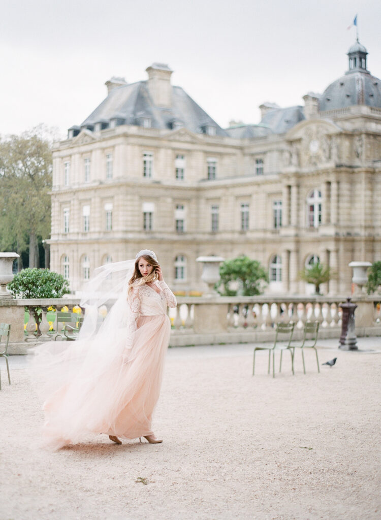 bride walking at ranunculus flower with cathedral veil blowing in the wind