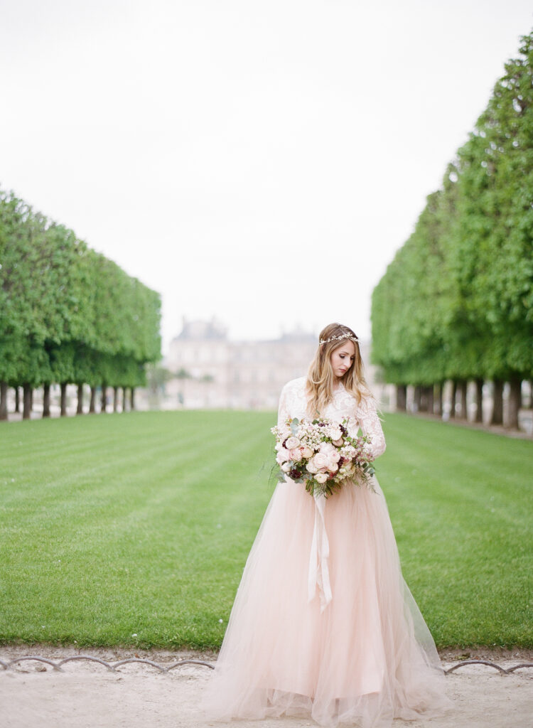 bride wearing blush gown in front of the green at jardin de luxembourg 