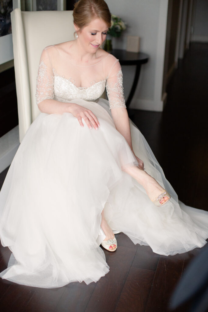 bride sitting putting on her badgley mischka shoes 