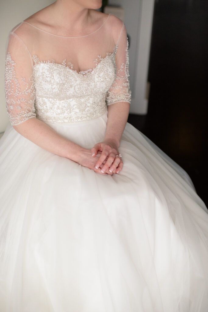 bride sitting in dress picture of ring on her finger in her lap