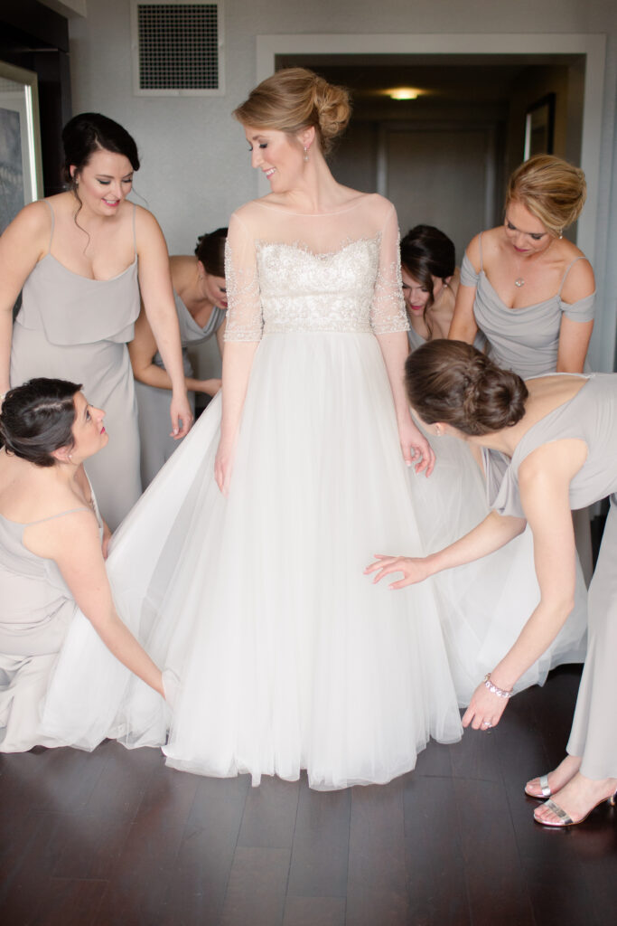 bridesmaids helping bride with her dress 