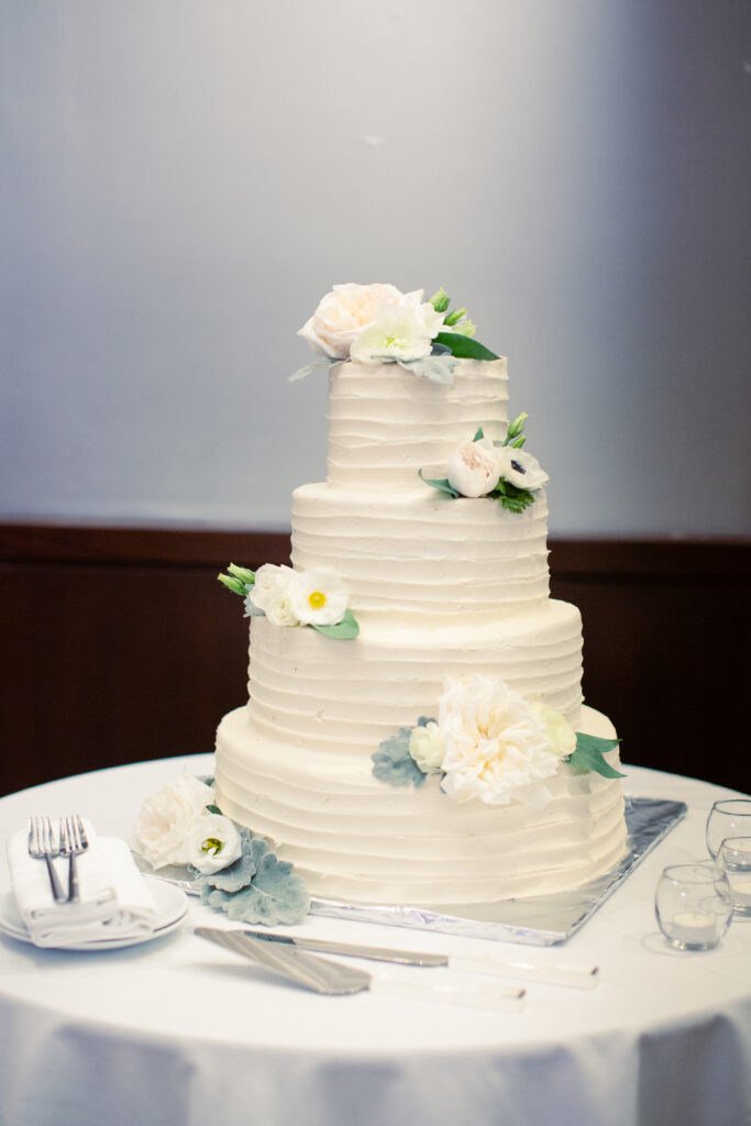 four tiered simple white wedding cake with flowers 