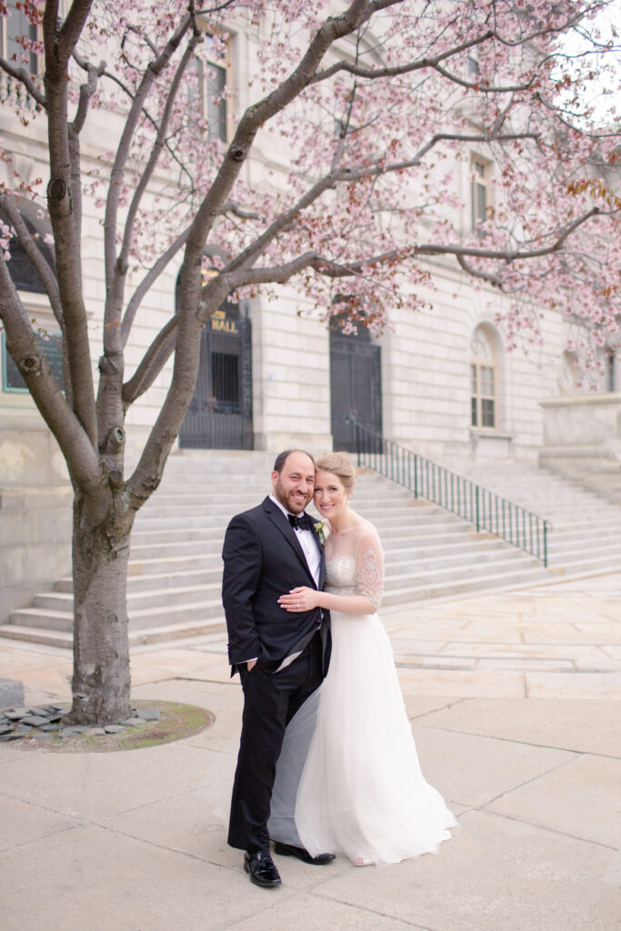 bride and groom under pink flowering tree 