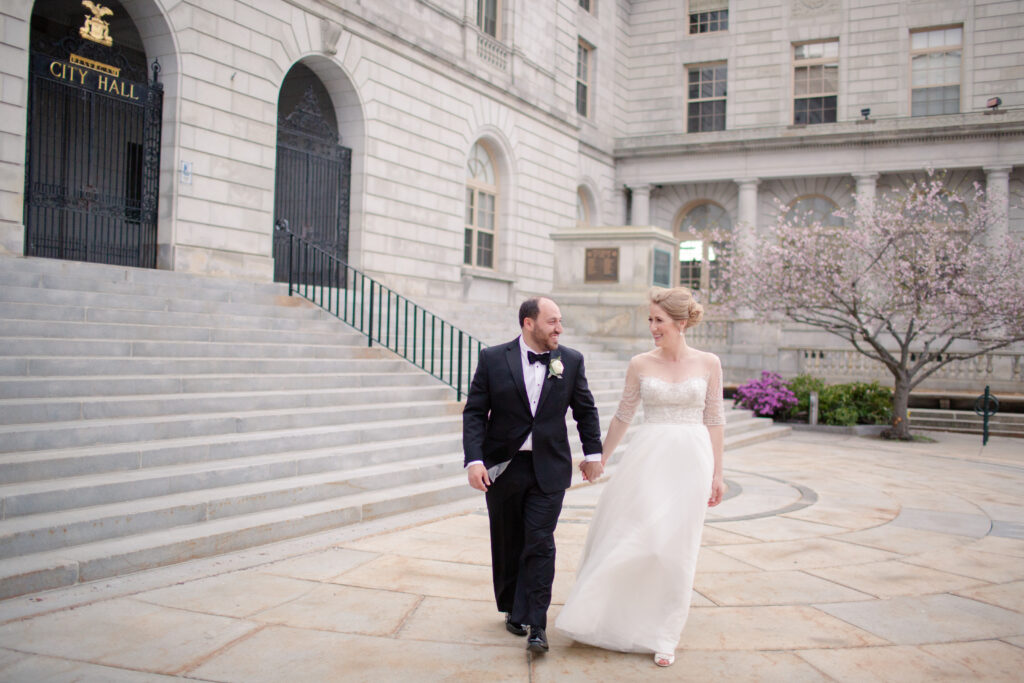 bride and groom walking outside of city hall