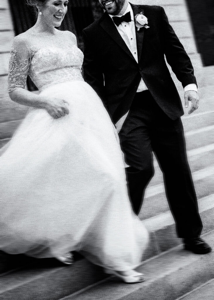 black and white of bride and groom walking down stairs 