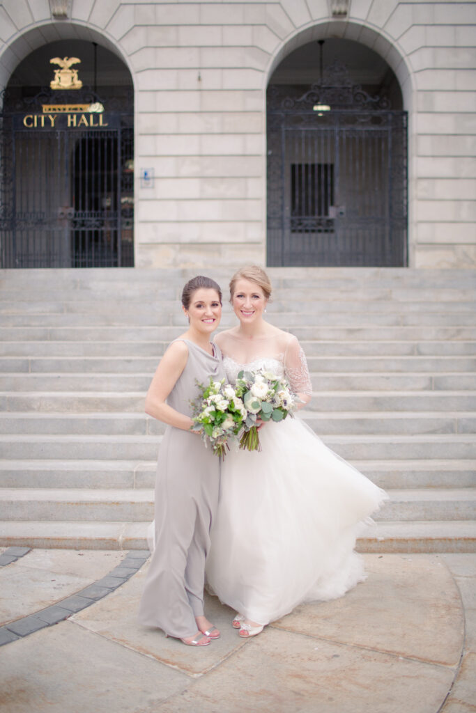 portrait of bride and sister together in front of city hall 