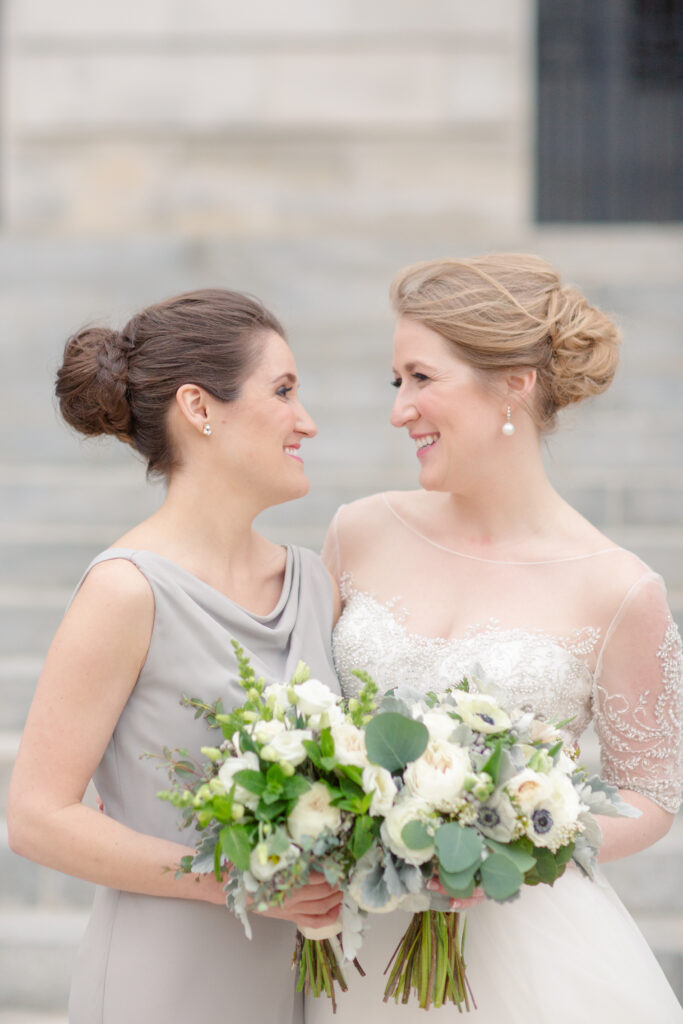 bride and sister smiling at each other 