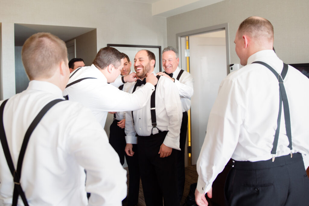 groomsmen helping groom with bowtie