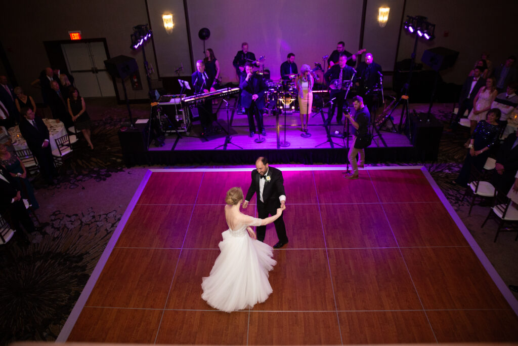 picture from the balcony of bride and groom dancing in ballroom with band in the background