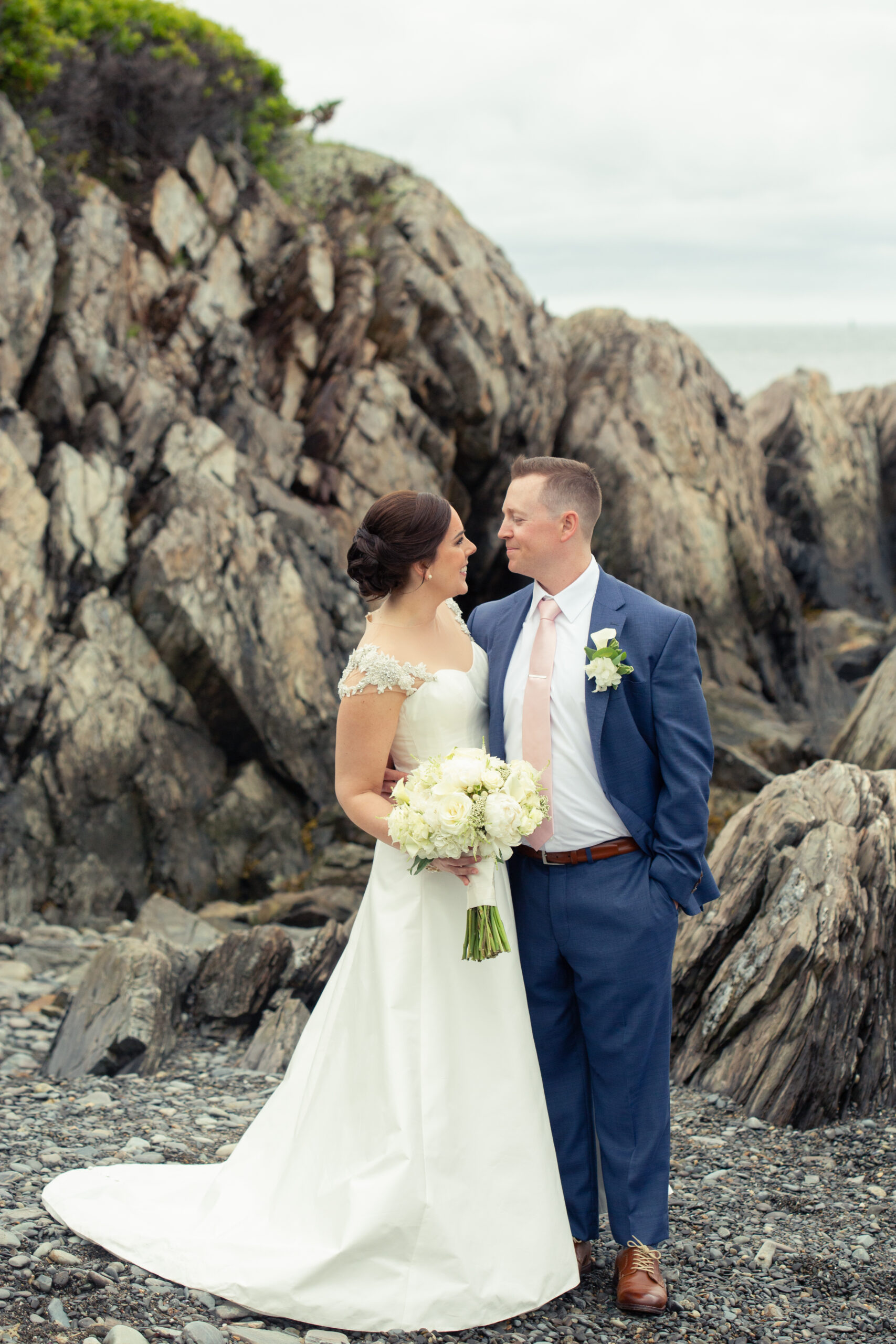 bride and groom on the rocks by the ocean